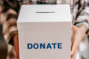 Close-up of a person holding a 'donate' box, encouraging charity and support.